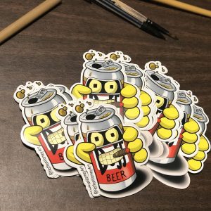 Recycled bender as a duff beer can stickers spread on table.